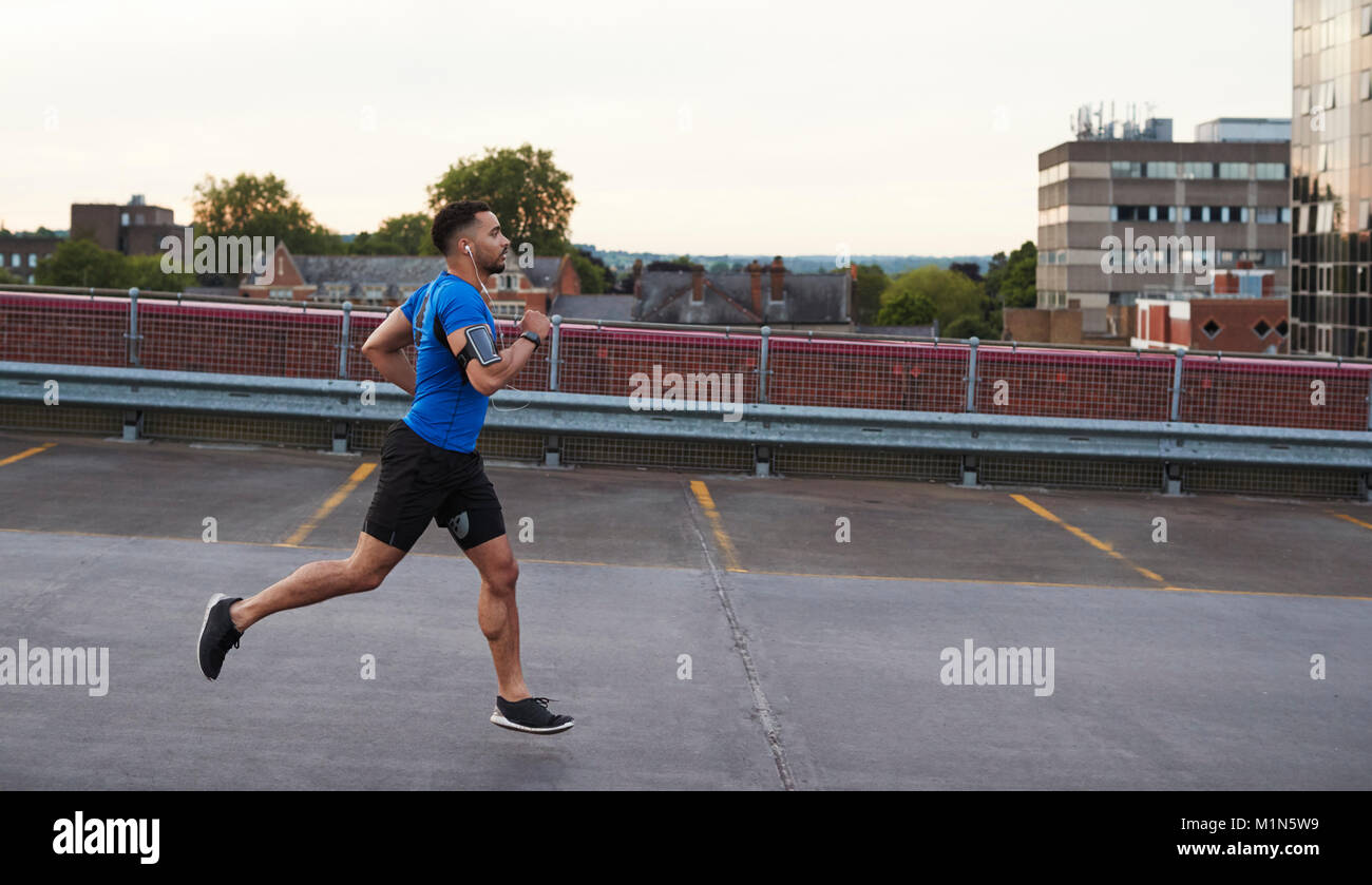 Young male athlete running on a road, side view Stock Photo