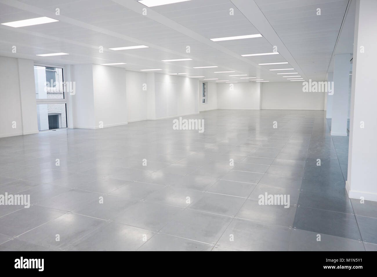 Vacant open plan office space with lights on Stock Photo