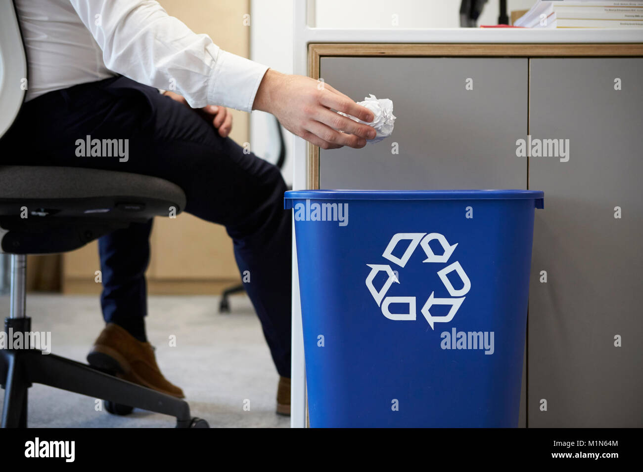 Man dropping screwed up paper into recycling bin, close up Stock Photo
