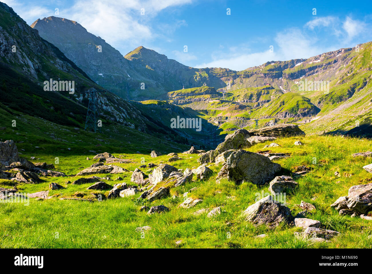 lovely scenery of Transfagarasan road in valley. rocks on grassy meadow and slopes. half of the valley in shade of mountain ridge Stock Photo