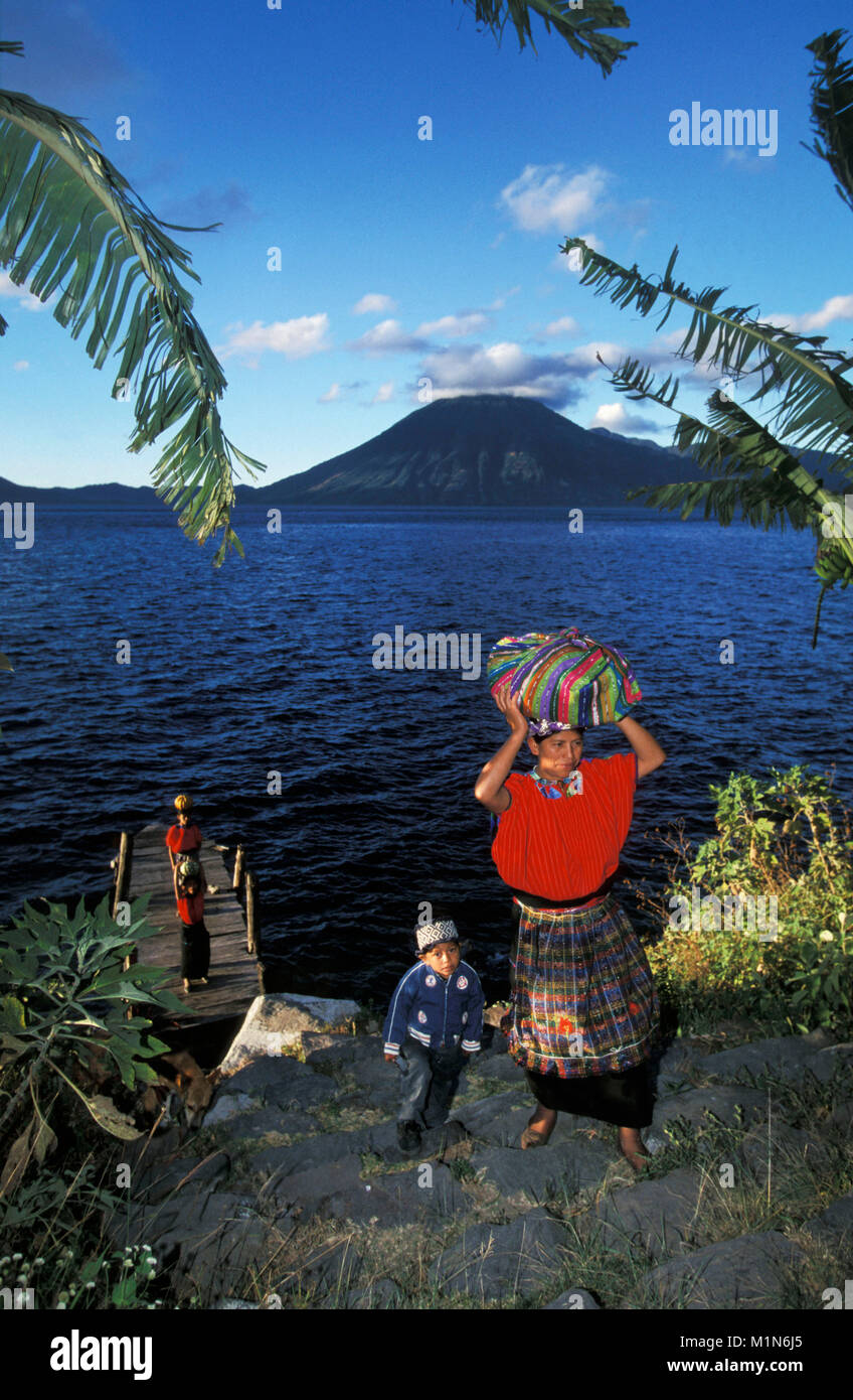 Guatemala. Panajachel. Lago de Atitlan. Maya mother and children coming on land. Transporting purchases on head. Stock Photo