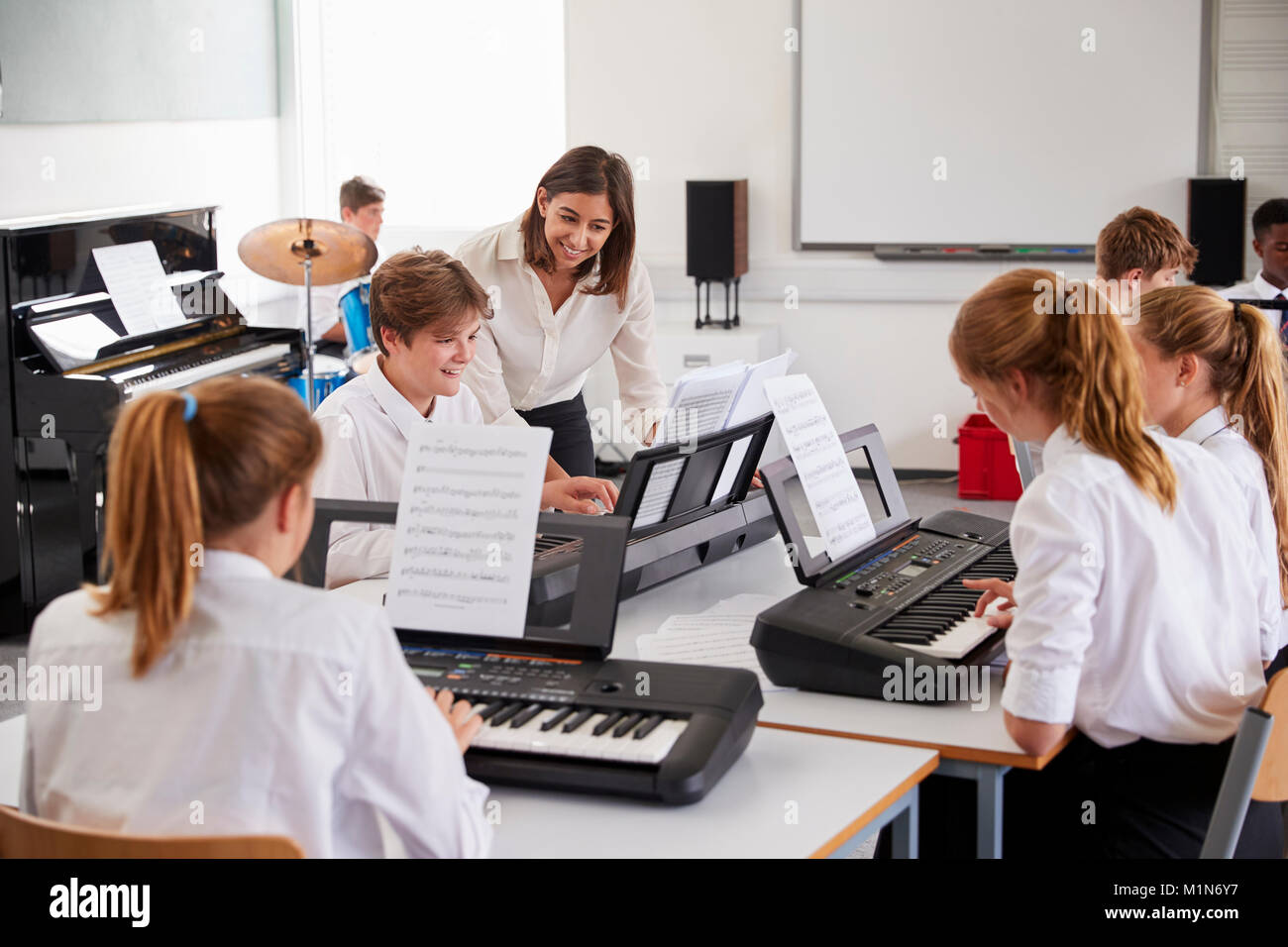 Teenage Students Studying Electronic Keyboard In Music Class Stock Photo