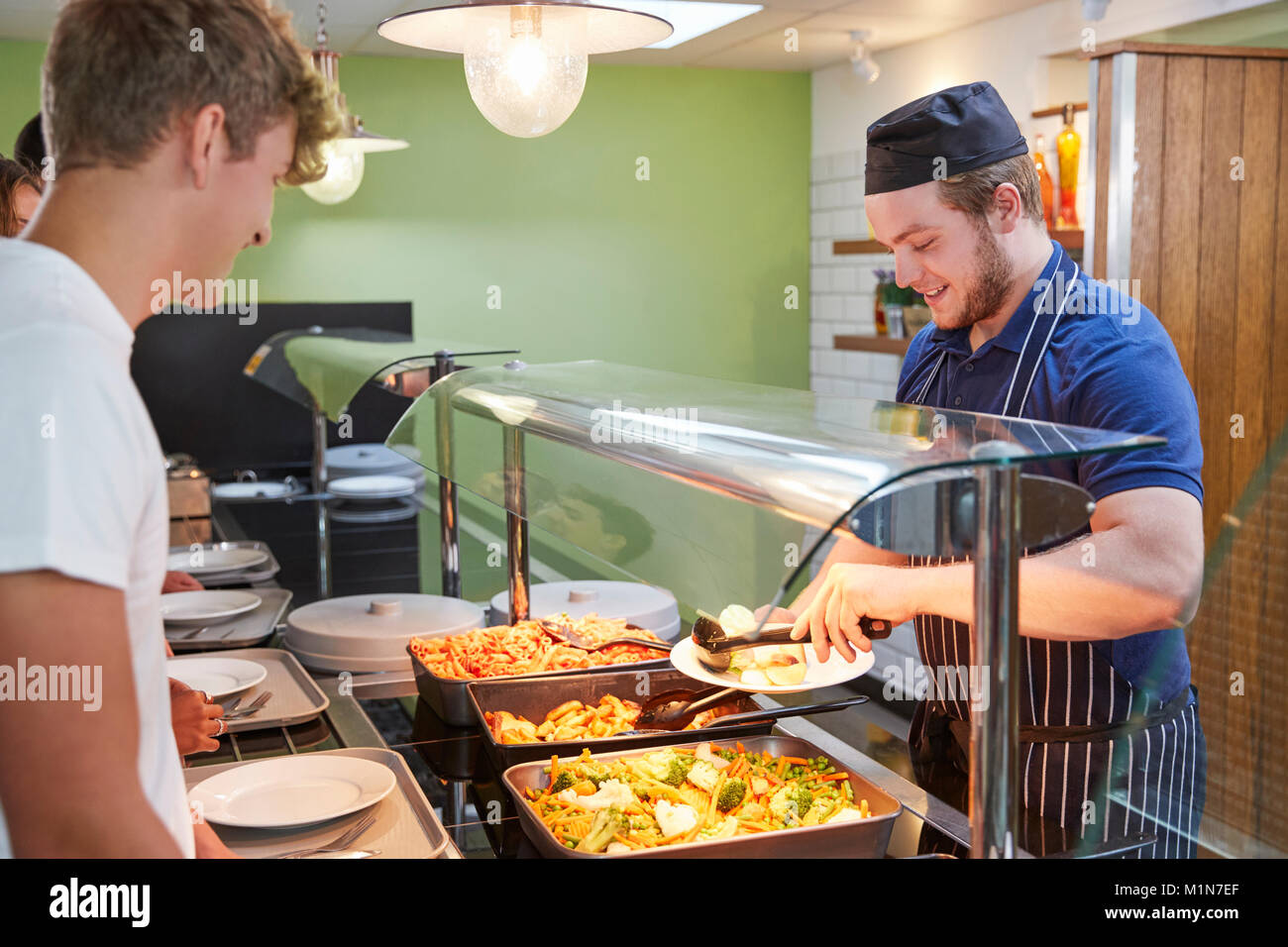 Teenage Students Being Served Meal In School Canteen Stock Photo