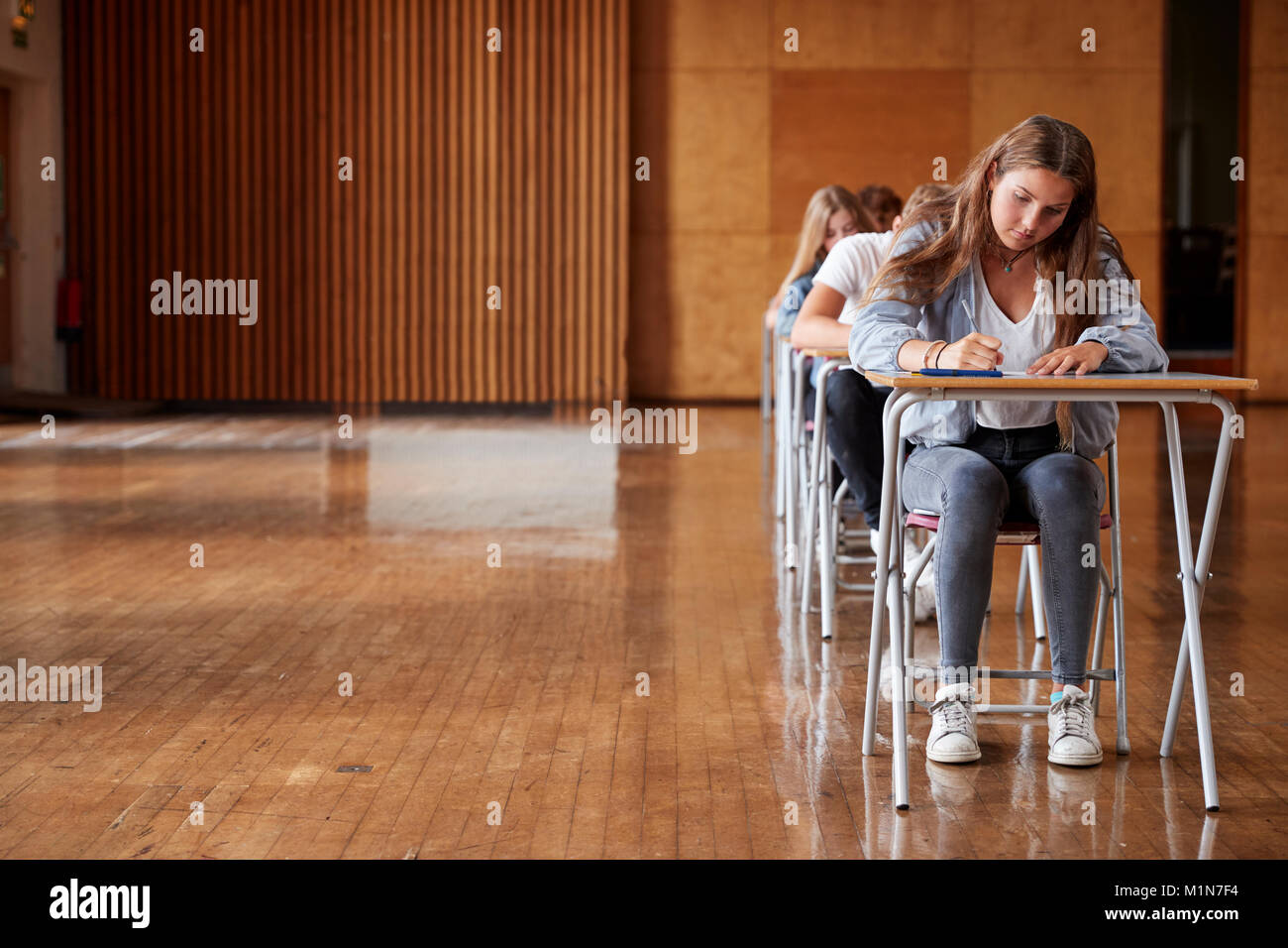 Group Of Teenage Students Sitting Examination In School Hall Stock Photo