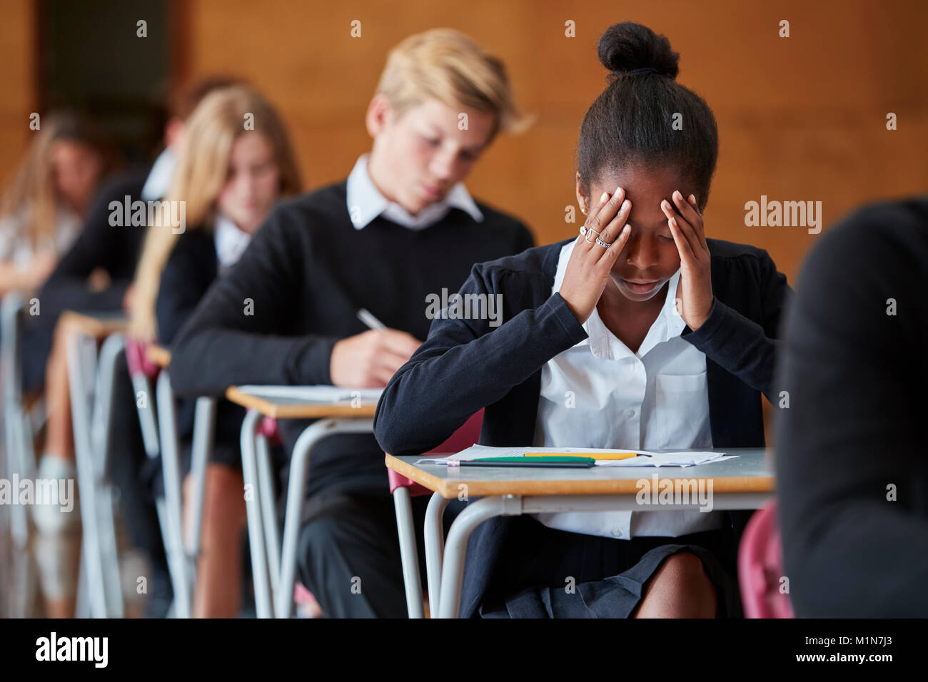 Anxious Teenage Student Sitting Examination In School Hall Stock Photo