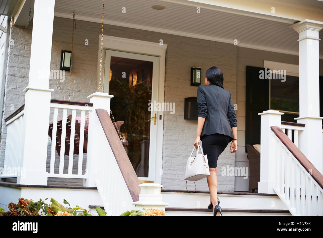 Businesswoman Returning To Suburban House After Work Stock Photo