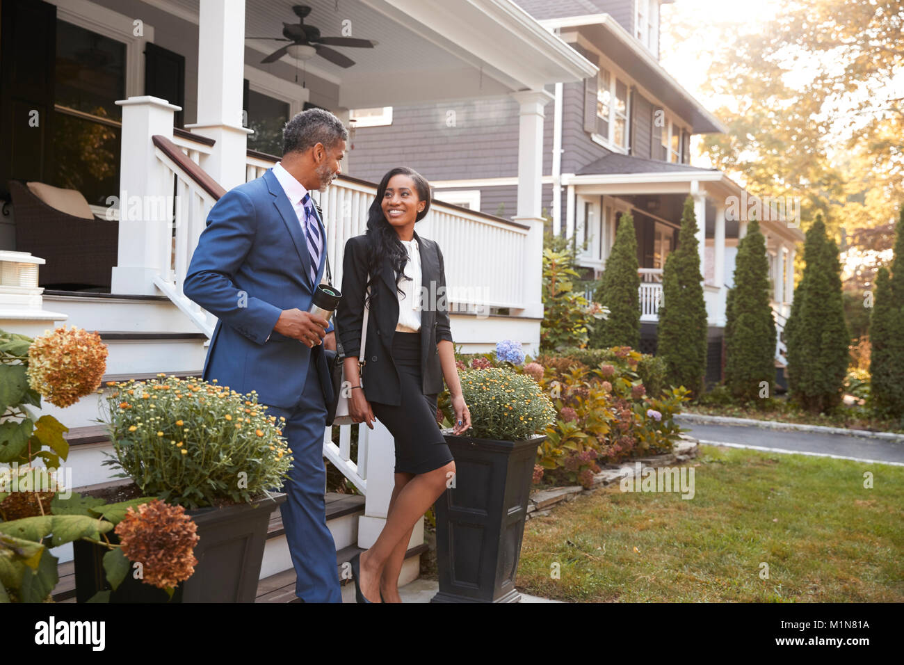 Business Couple Leaving Suburban House For Commute To Work Stock Photo
