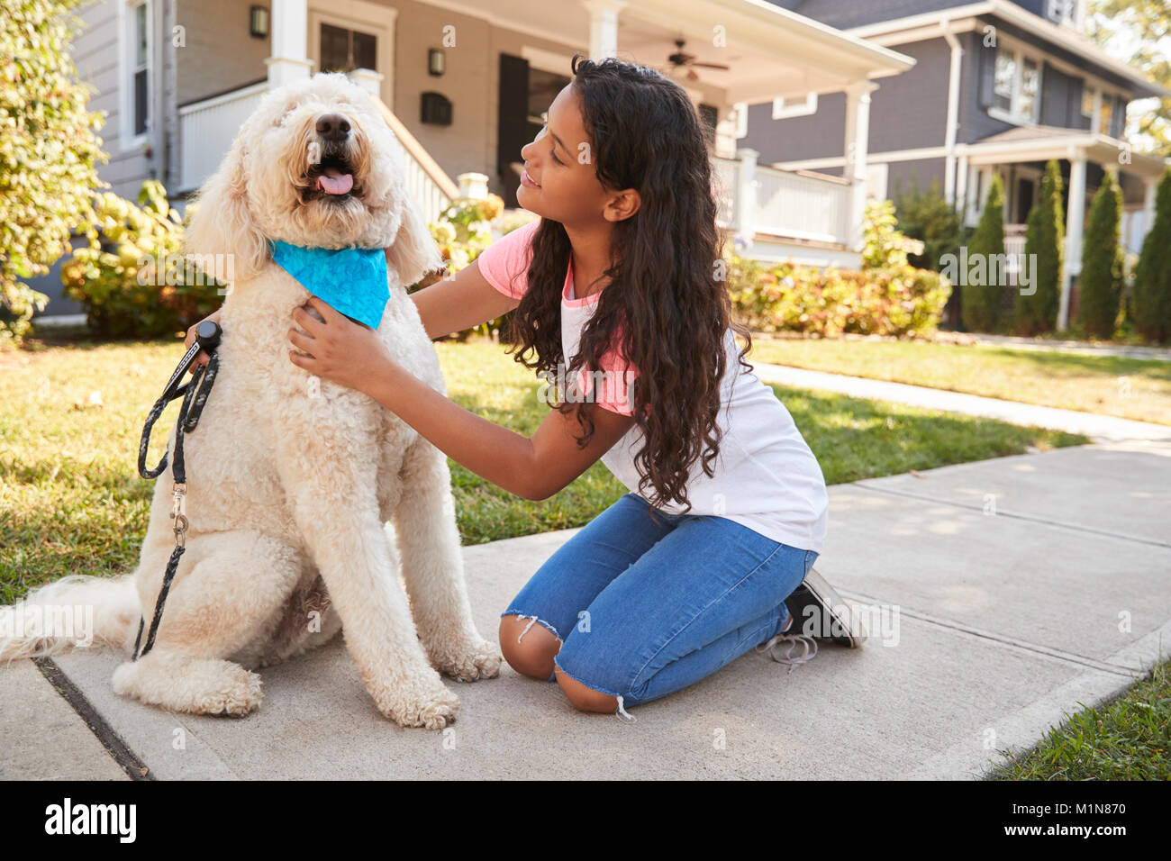 Girl Walking Dog Along Suburban Street Stock Photo