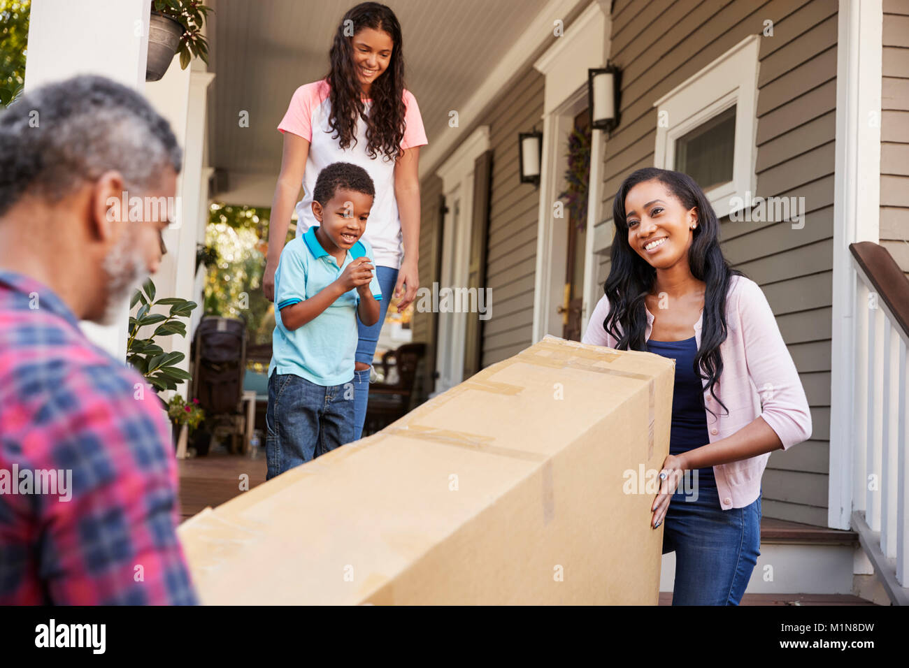 Family Carrying Big Box Purchase Into House Stock Photo