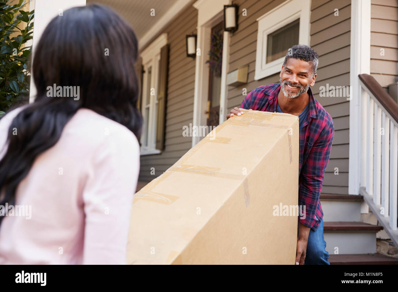 Couple Carrying Big Box Purchase Into House Stock Photo