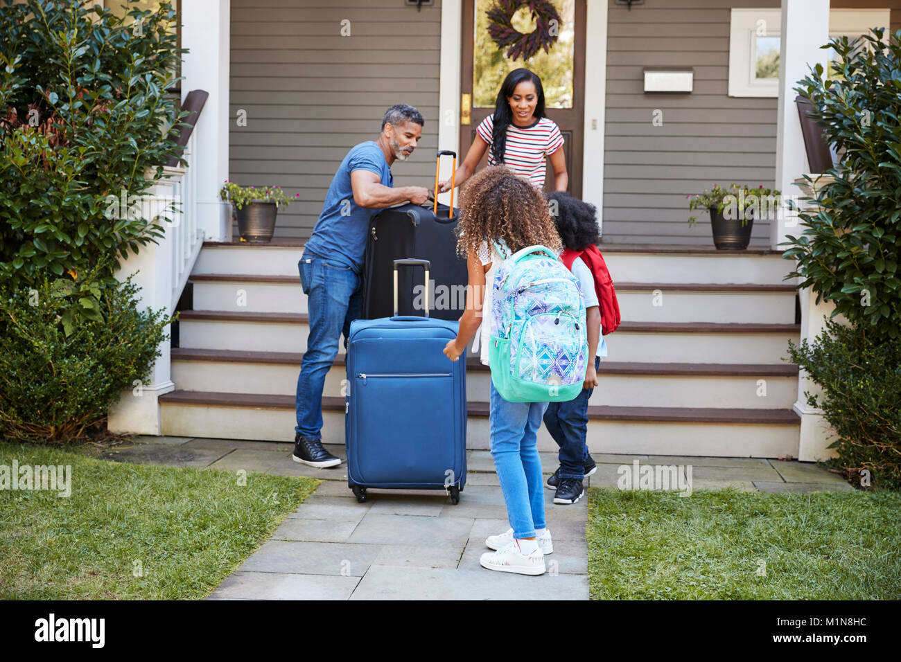 Family With Luggage Leaving House For Vacation Stock Photo