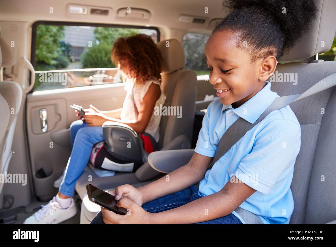 Children Using Digital Devices On Car Journey Stock Photo
