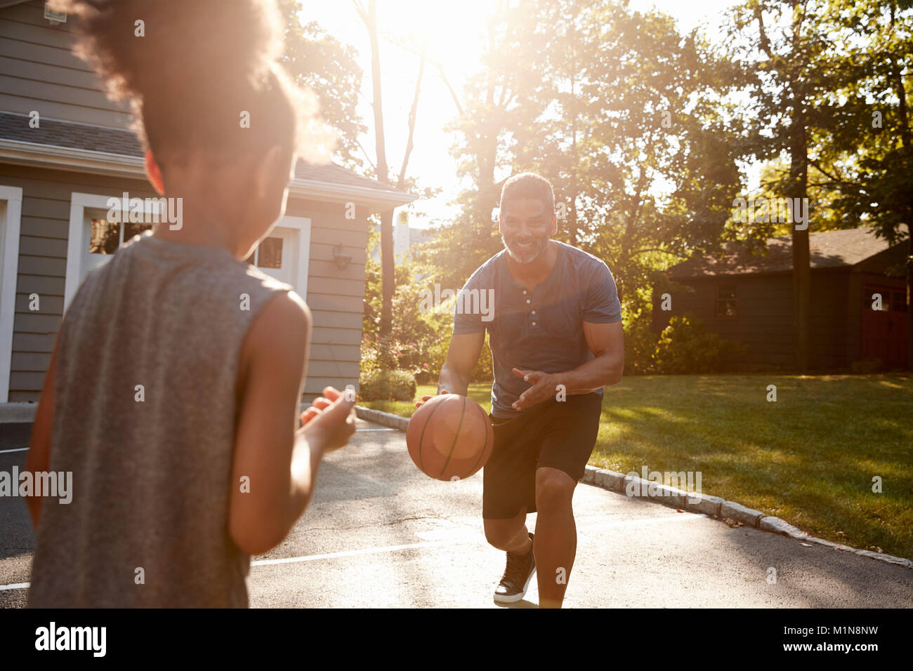 Father And Son Playing Basketball On Driveway At Home Stock Photo