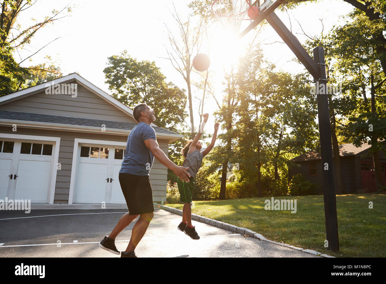 Father And Son Playing Basketball On Driveway At Home Stock Photo