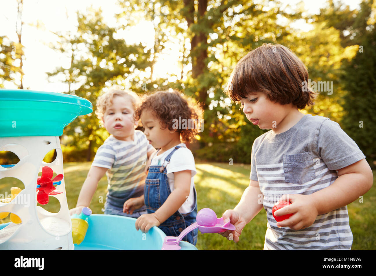 Group Of Young Children Playing With Water Table In Garden Stock Photo