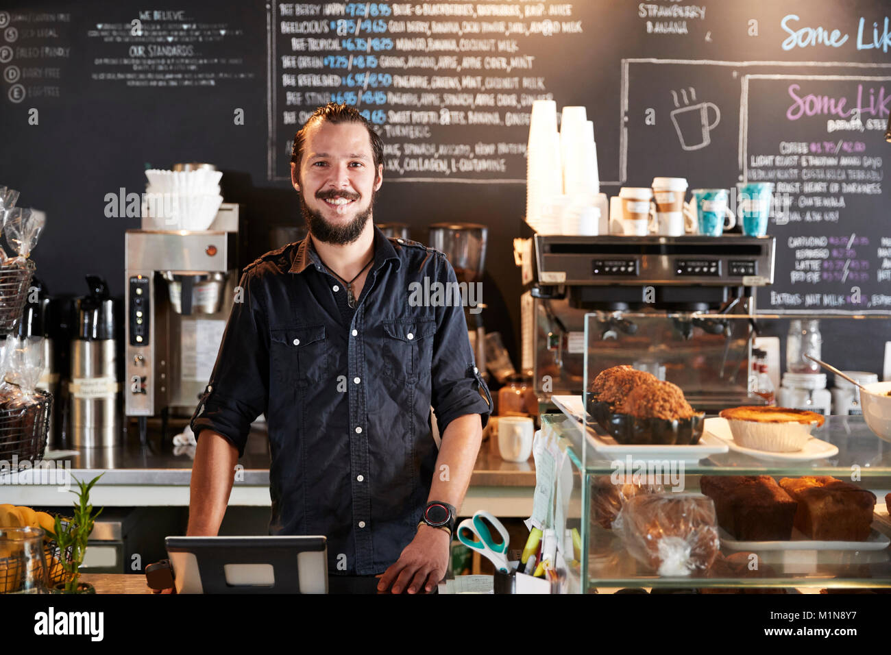 Portrait Of Male Barista Behind Counter In Coffee Shop Stock Photo