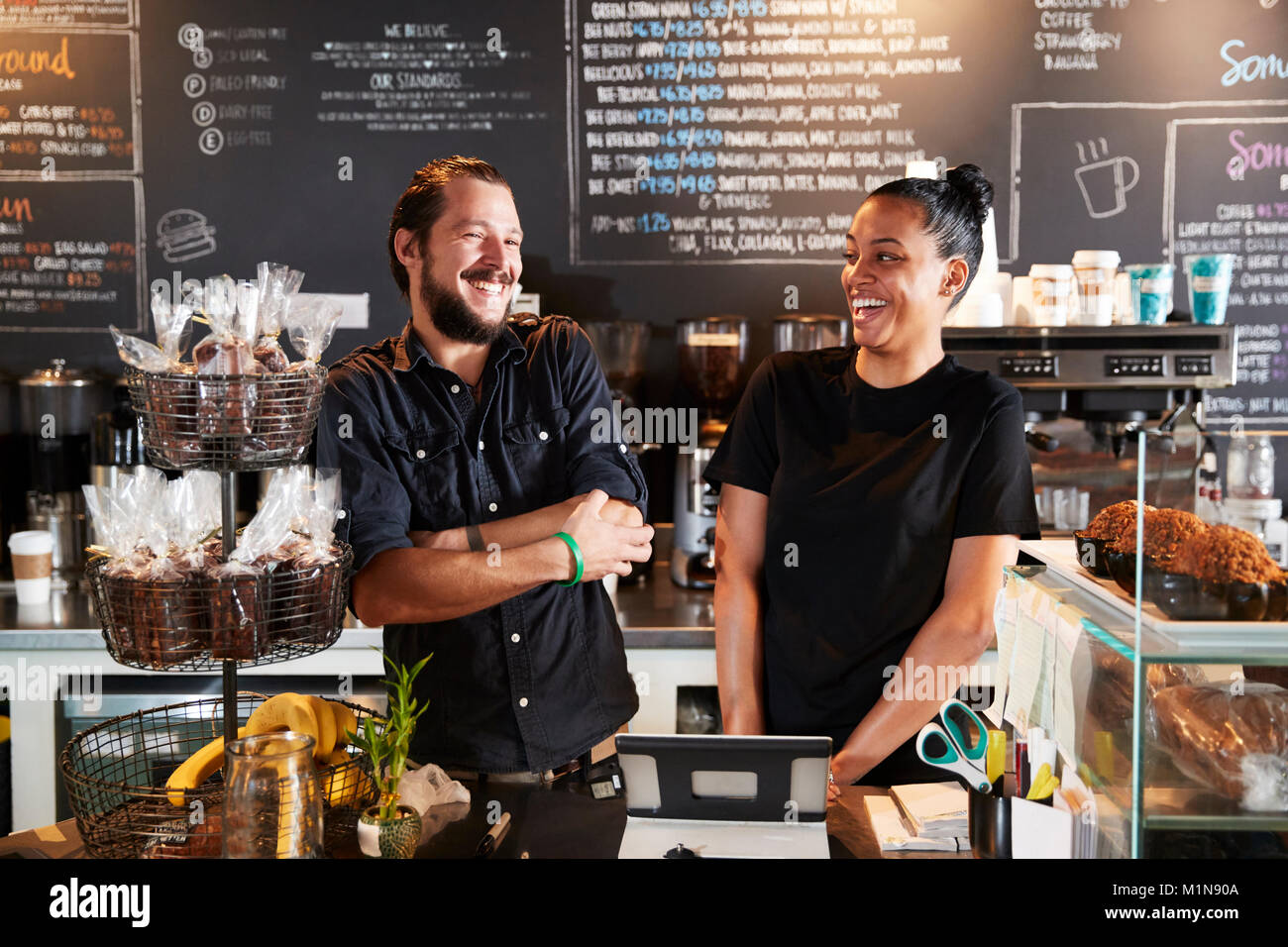 Male And Female Baristas Behind Counter In Coffee Shop Stock Photo