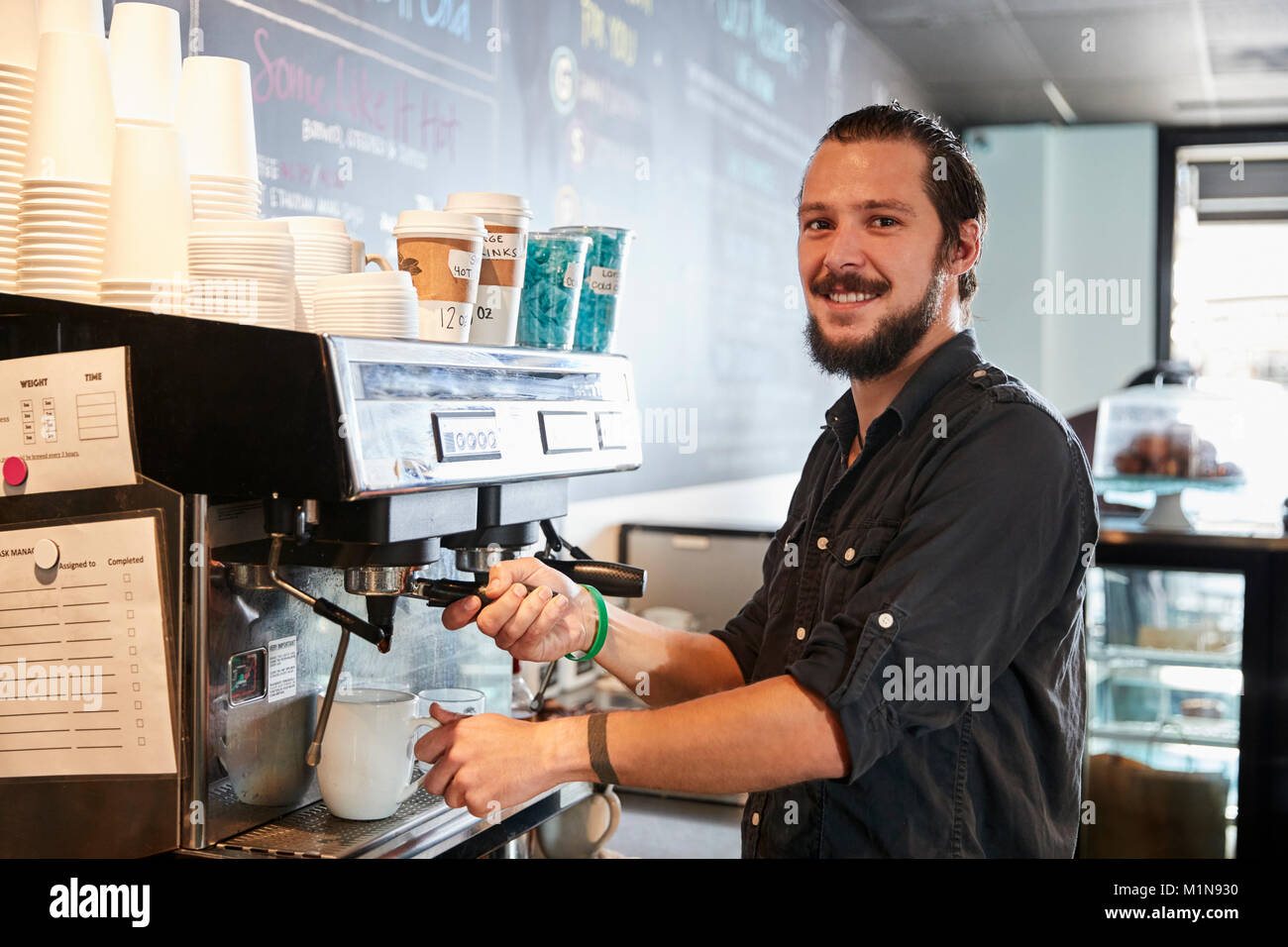 Portrait Of Male Barista Behind Counter In Coffee Shop Stock Photo