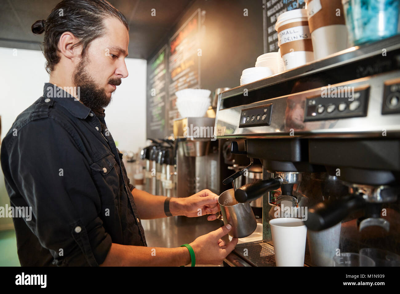 Male Barista Using Coffee Machine Behind Counter In Cafe Stock Photo