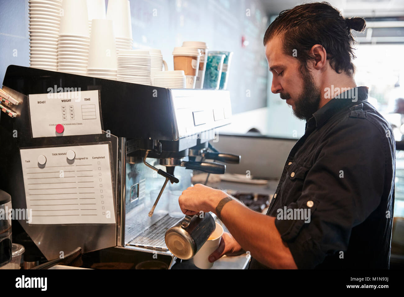 Male Barista Using Coffee Machine Behind Counter In Cafe Stock Photo