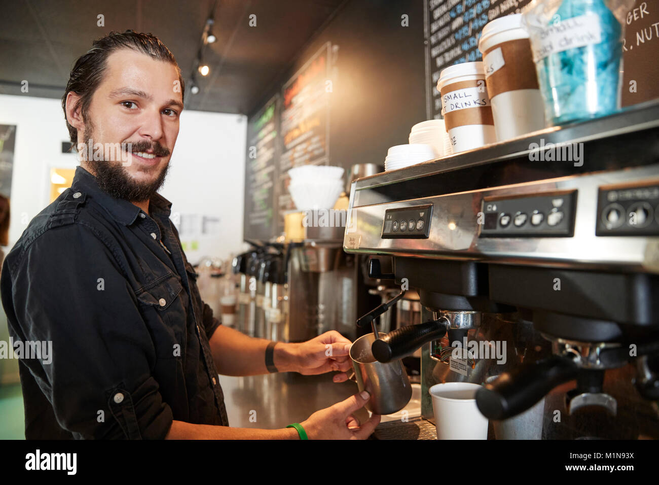 Portrait Of Male Barista Behind Counter In Coffee Shop Stock Photo