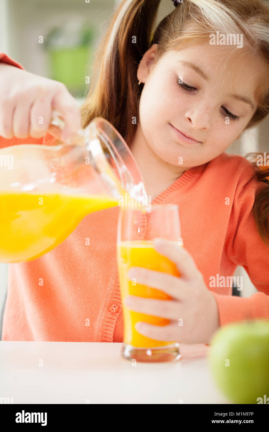 A little girl drinking a juice at home Stock Photo