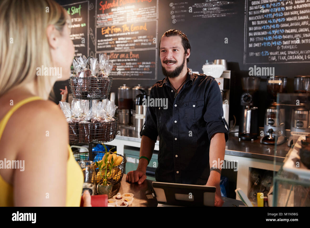 Waiter Taking Female Customer's Order In Coffee Shop Stock Photo