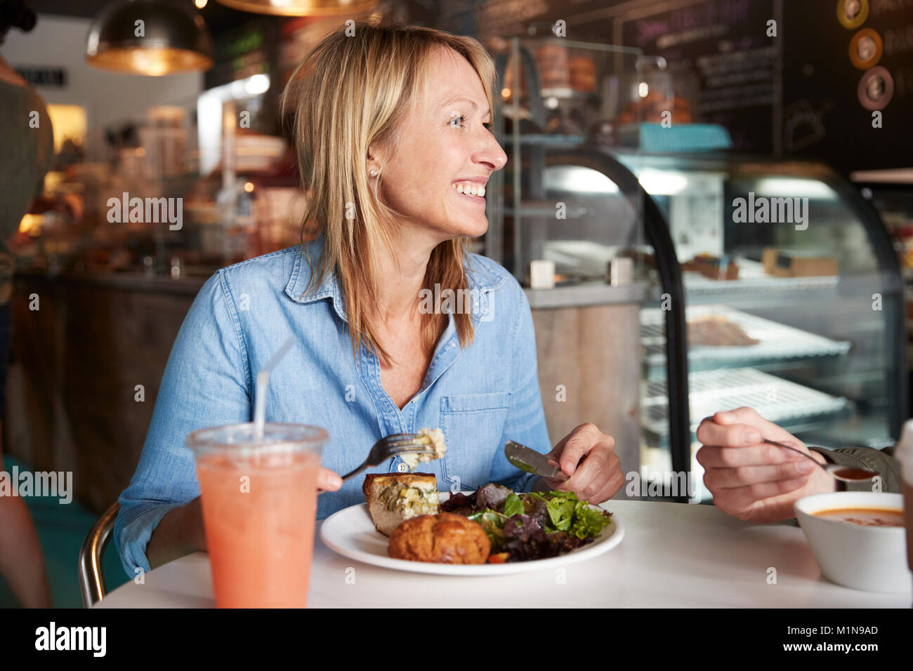 Woman In Coffee Shop Sitting At Table Eating Healthy Lunch Stock Photo