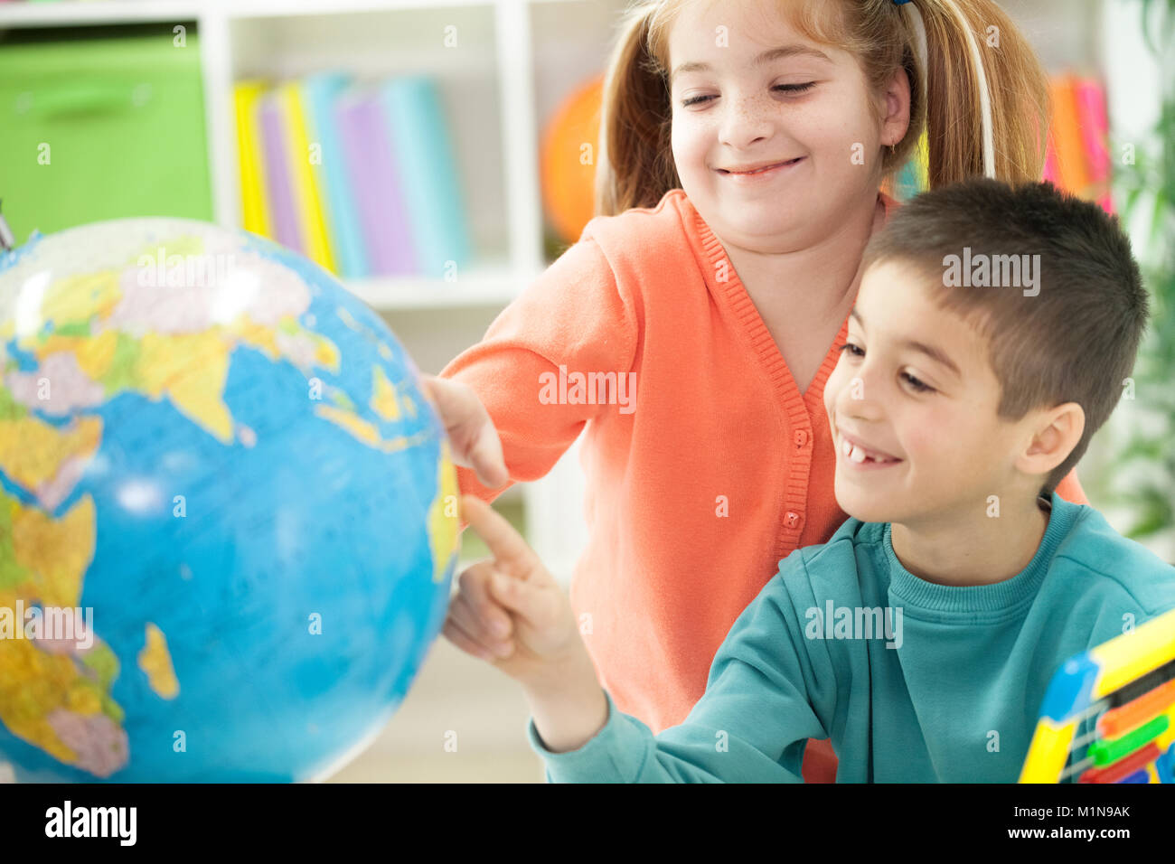 young brother sister shows place on the globe, together teach geography Stock Photo