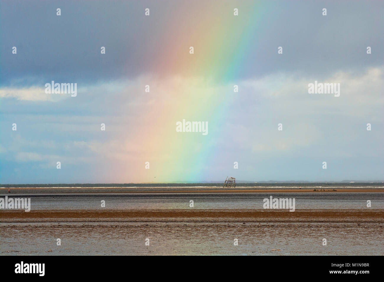 Rainbow over remains of the Wyre Light, a 40-foot  tall iron screw-pile lighthouse marking the navigation channel to the town of Fleetwood, Lancashire Stock Photo