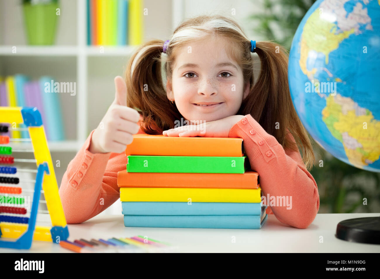 Little girl holding pile of books at home Stock Photo - Alamy