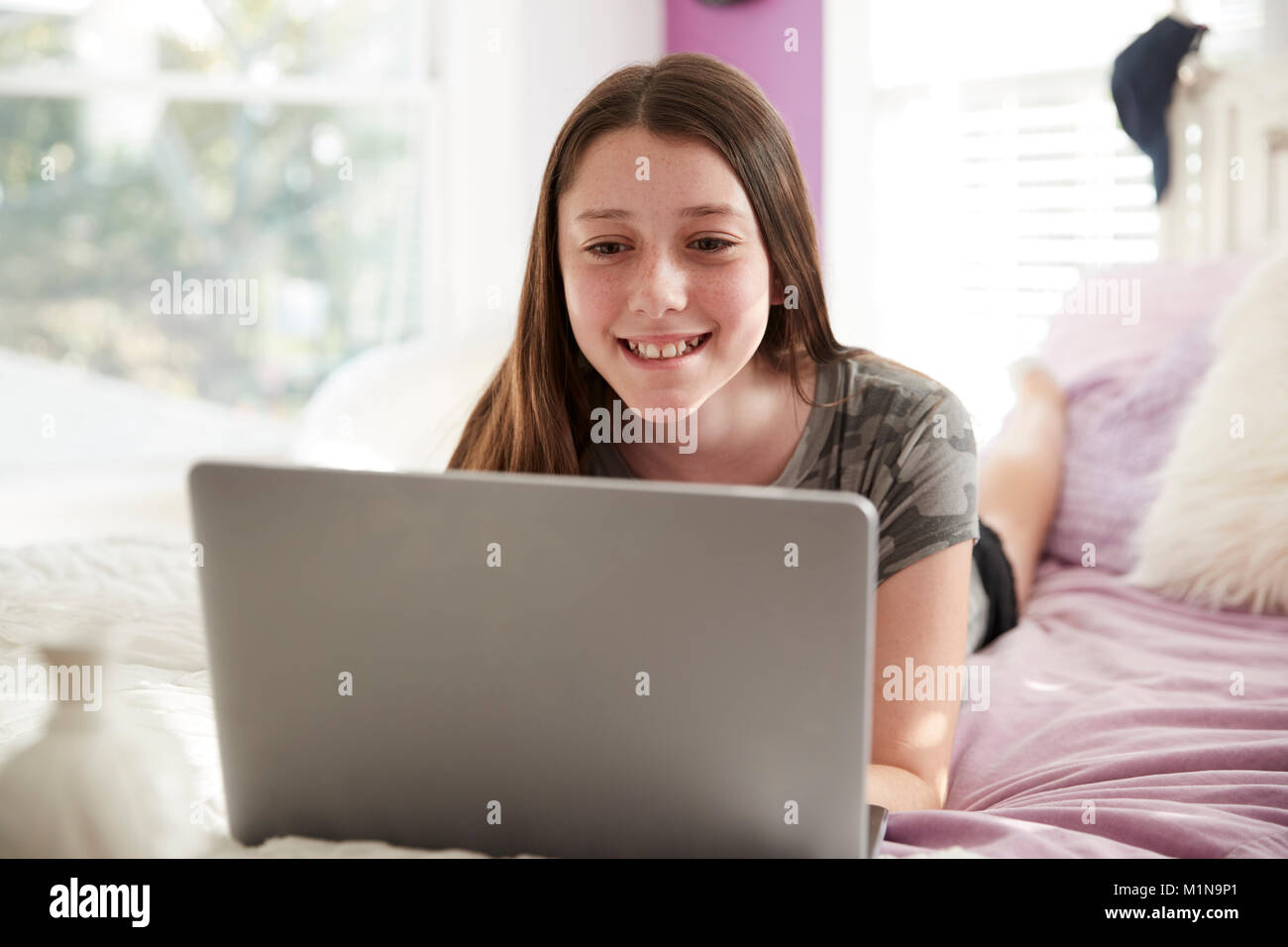 Teenage girl lying on bed using a laptop computer, close up Stock Photo