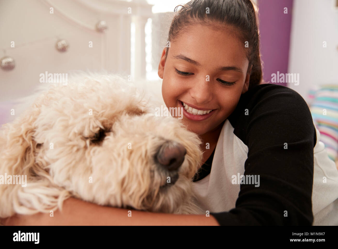 Young teen girl embracing pet dog on her bed, close up Stock Photo