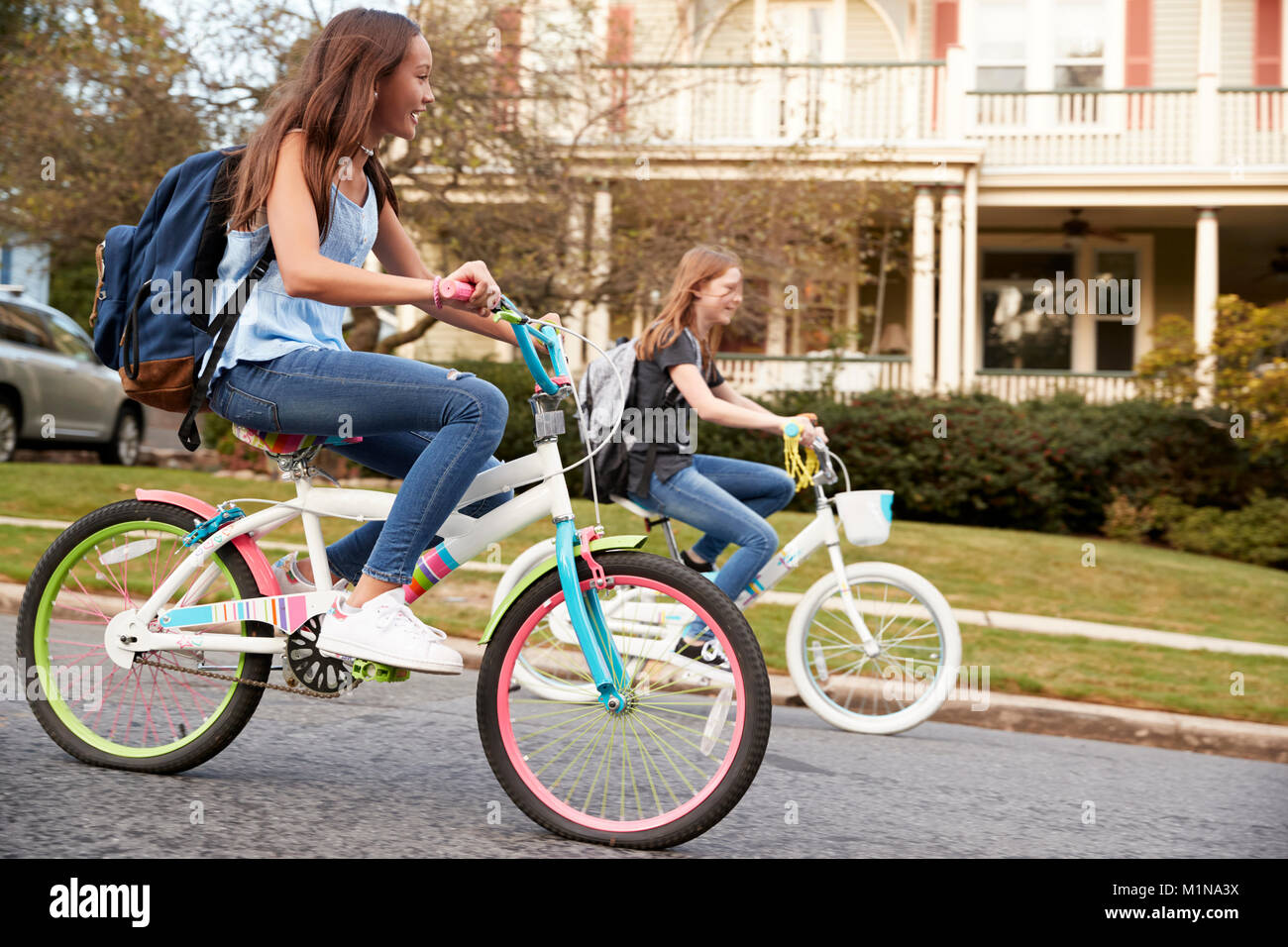 Two teen girls riding bikes in street, side view close up Stock Photo -  Alamy