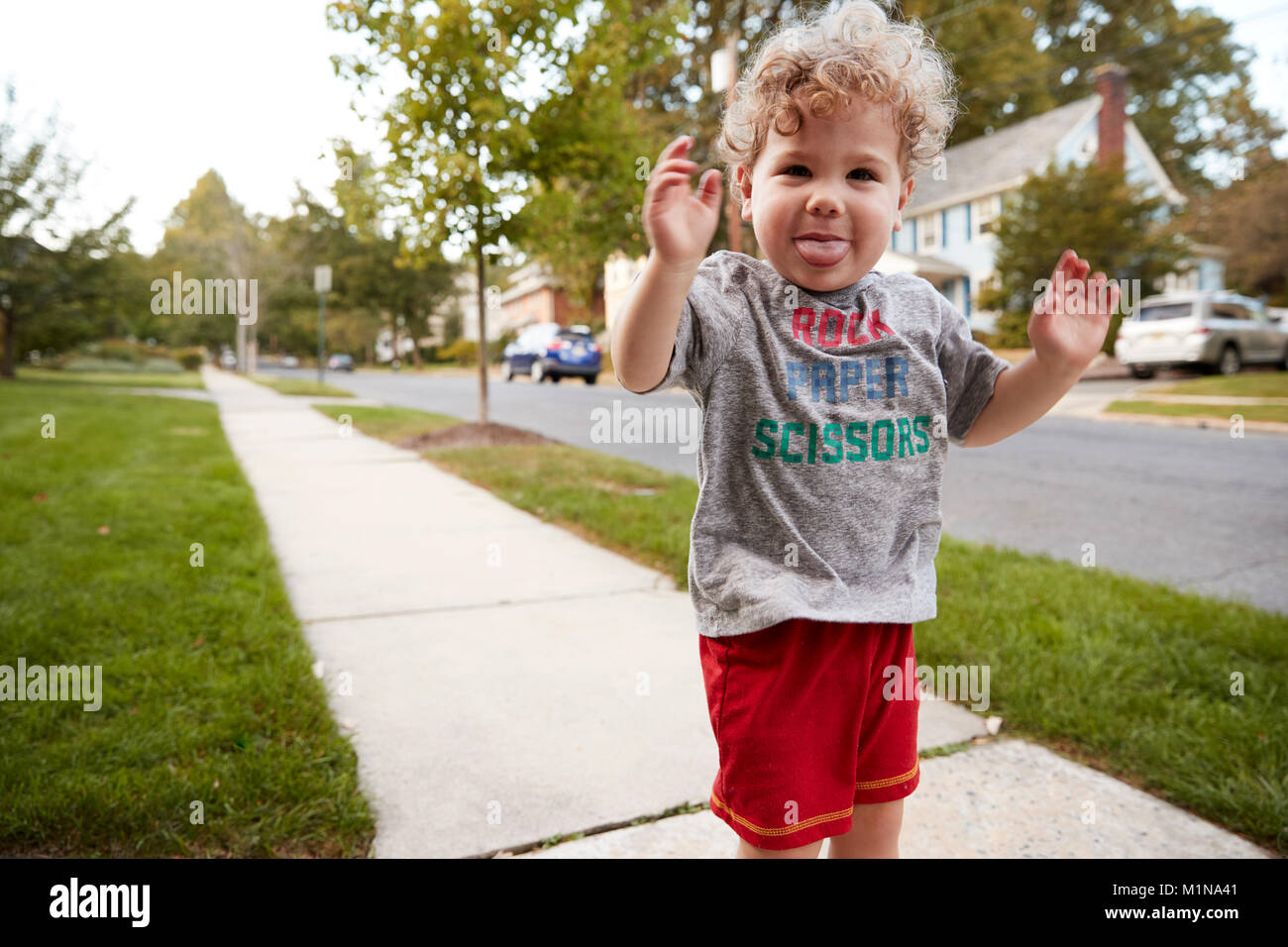 Toddler boy standing in the street making a face to camera Stock Photo