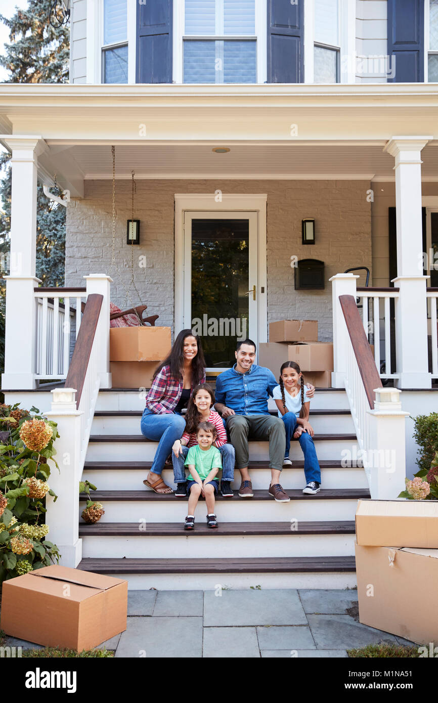 Family Sitting On Steps Of New Home On Moving In Day Stock Photo