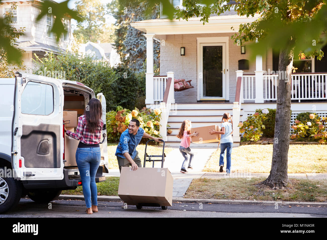 Children Helping Unload Boxes From Van On Family Moving In Day Stock Photo