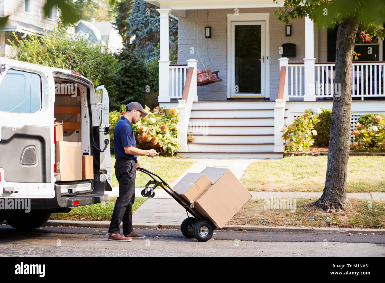 Courier Knocking On Door Of House To Deliver Package Stock Photo