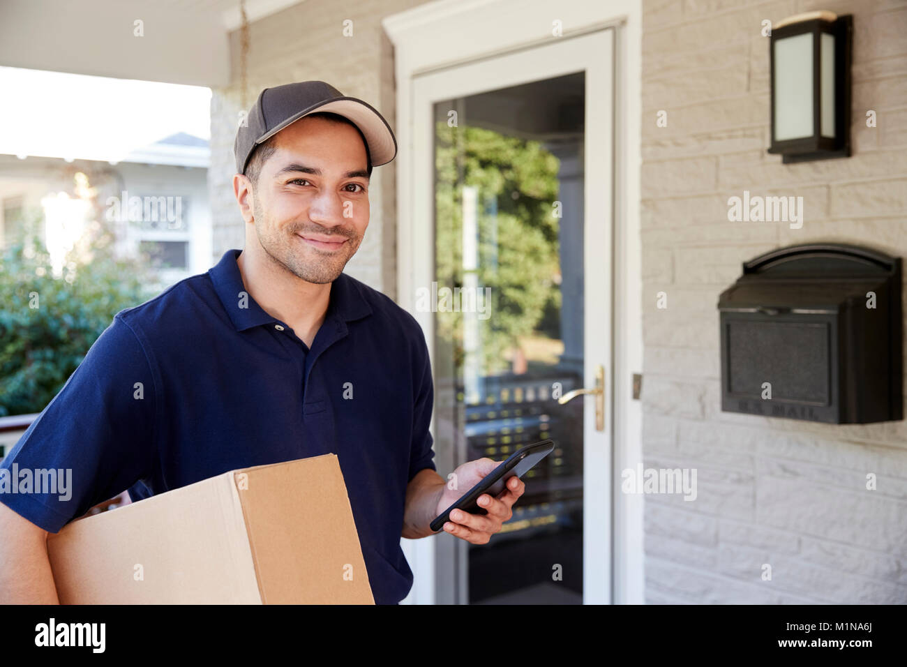 Portrait Of Courier With Digital Tablet Delivering Package Stock Photo