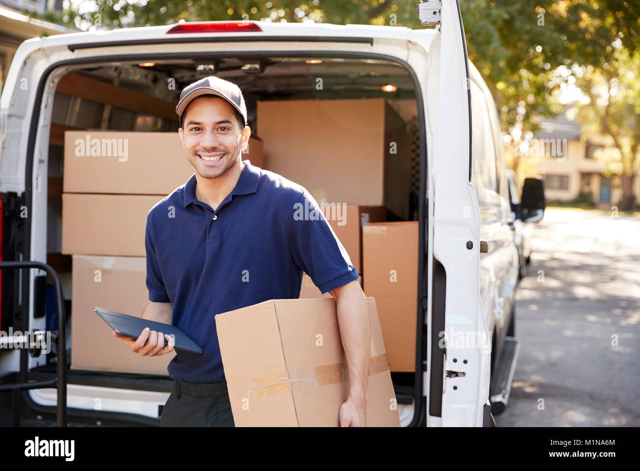 Portrait Of Courier With Digital Tablet Delivering Package Stock Photo