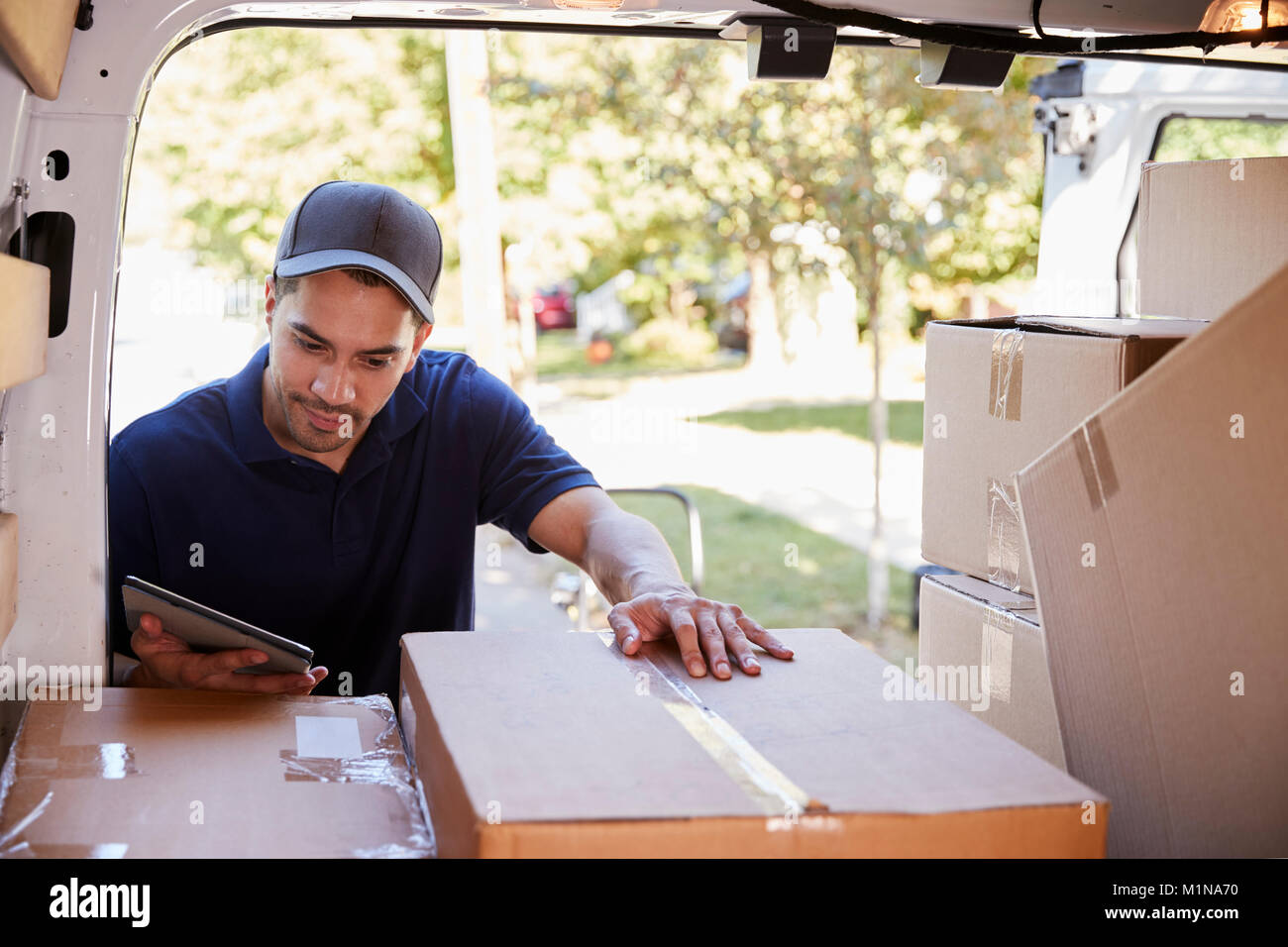 Courier With Digital Tablet Checking Packages In Van Stock Photo