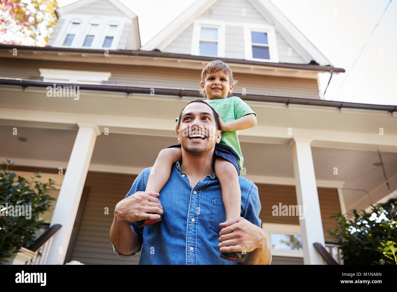 Father Giving Son Ride On Shoulders Outside House Stock Photo
