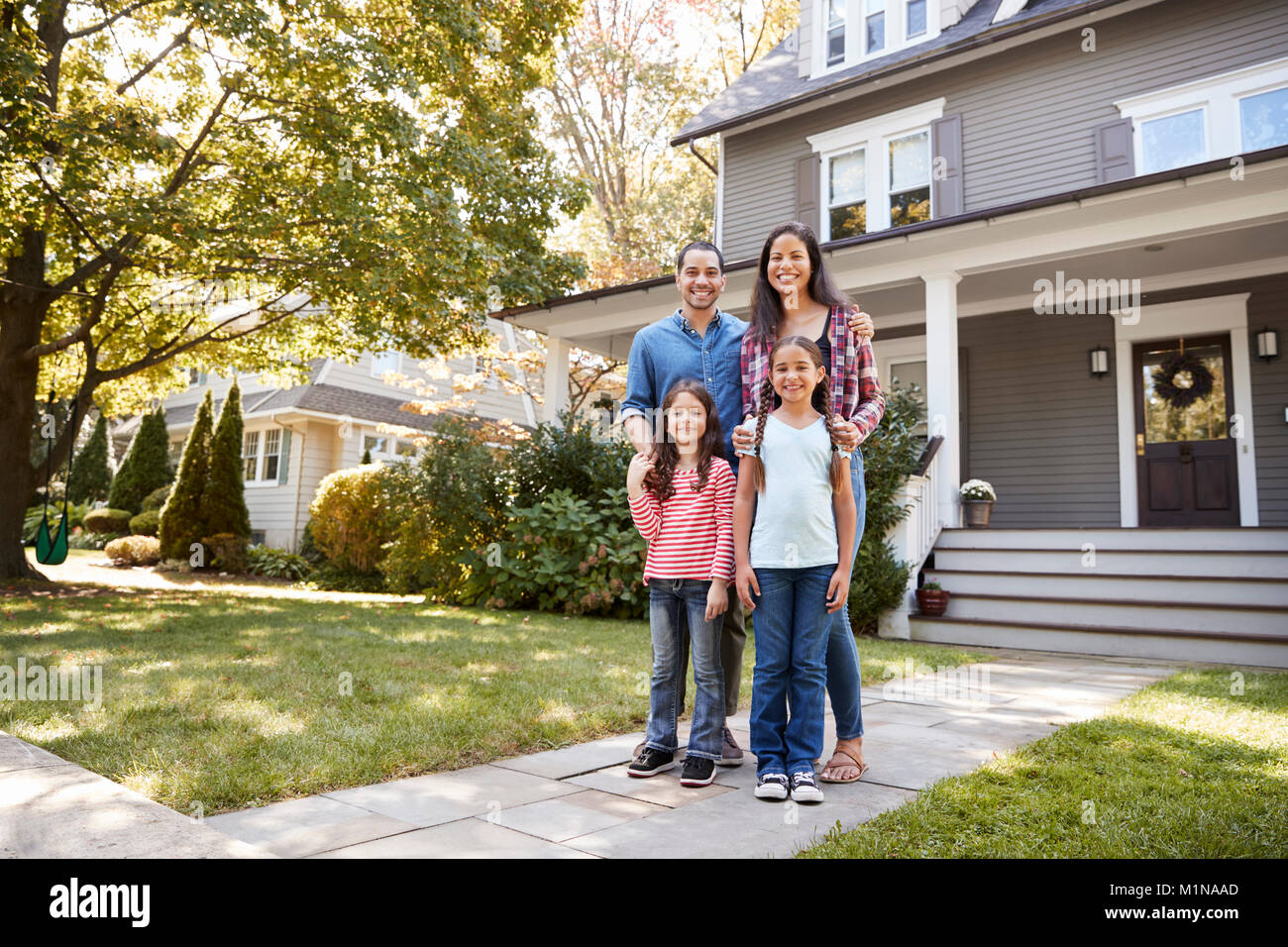 Portrait Of Smiling Family Standing In Front Of Their Home Stock Photo