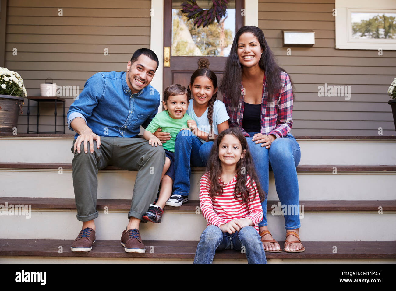 Portrait Of Family Sitting On Steps in Front Of House Stock Photo