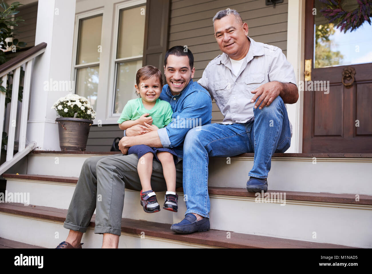 Male Multi Generation Family Sitting On Steps in Front Of House Stock Photo