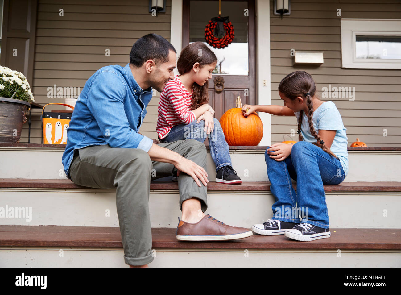 Father And Daughters Drawing Face On Halloween Pumpkin Stock Photo