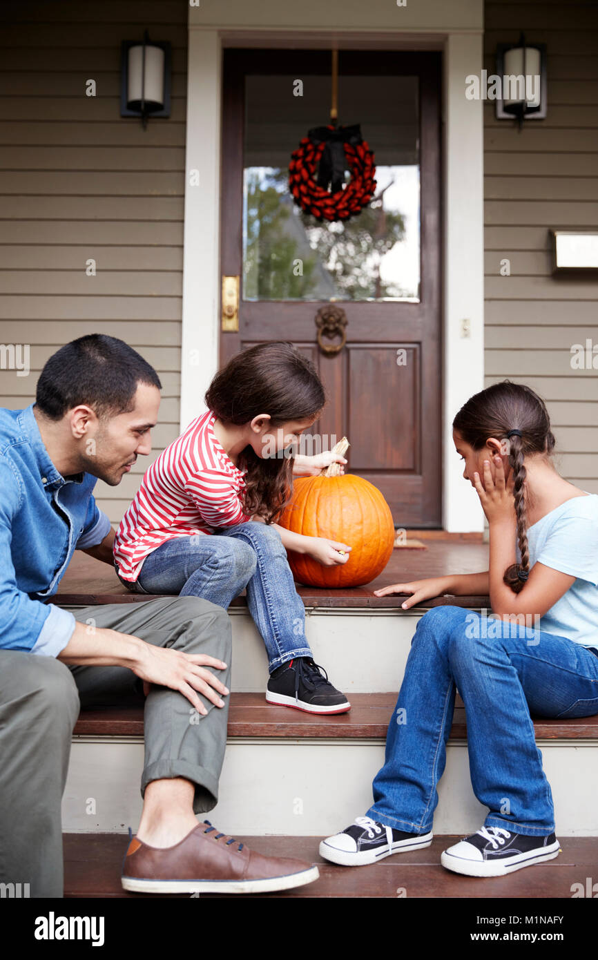 Father And Daughters Drawing Face On Halloween Pumpkin Stock Photo