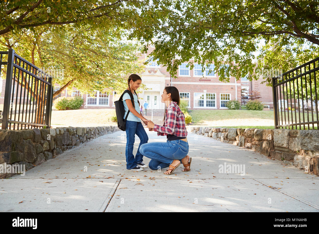 Mother Dropping Off Daughter In Front Of School Gates Stock Photo