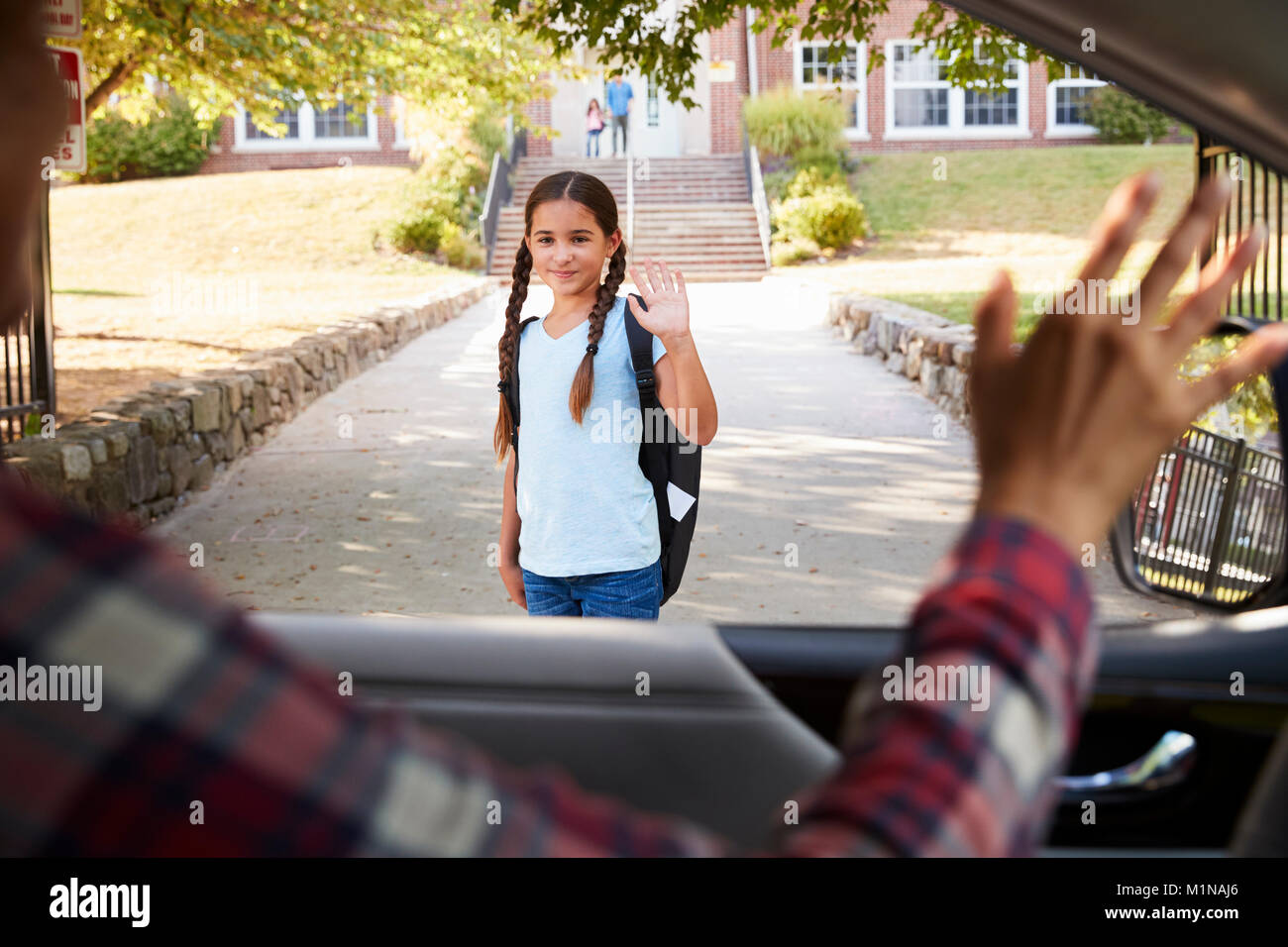 Mother In Car Dropping Off Daughter In Front Of School Gates Stock Photo