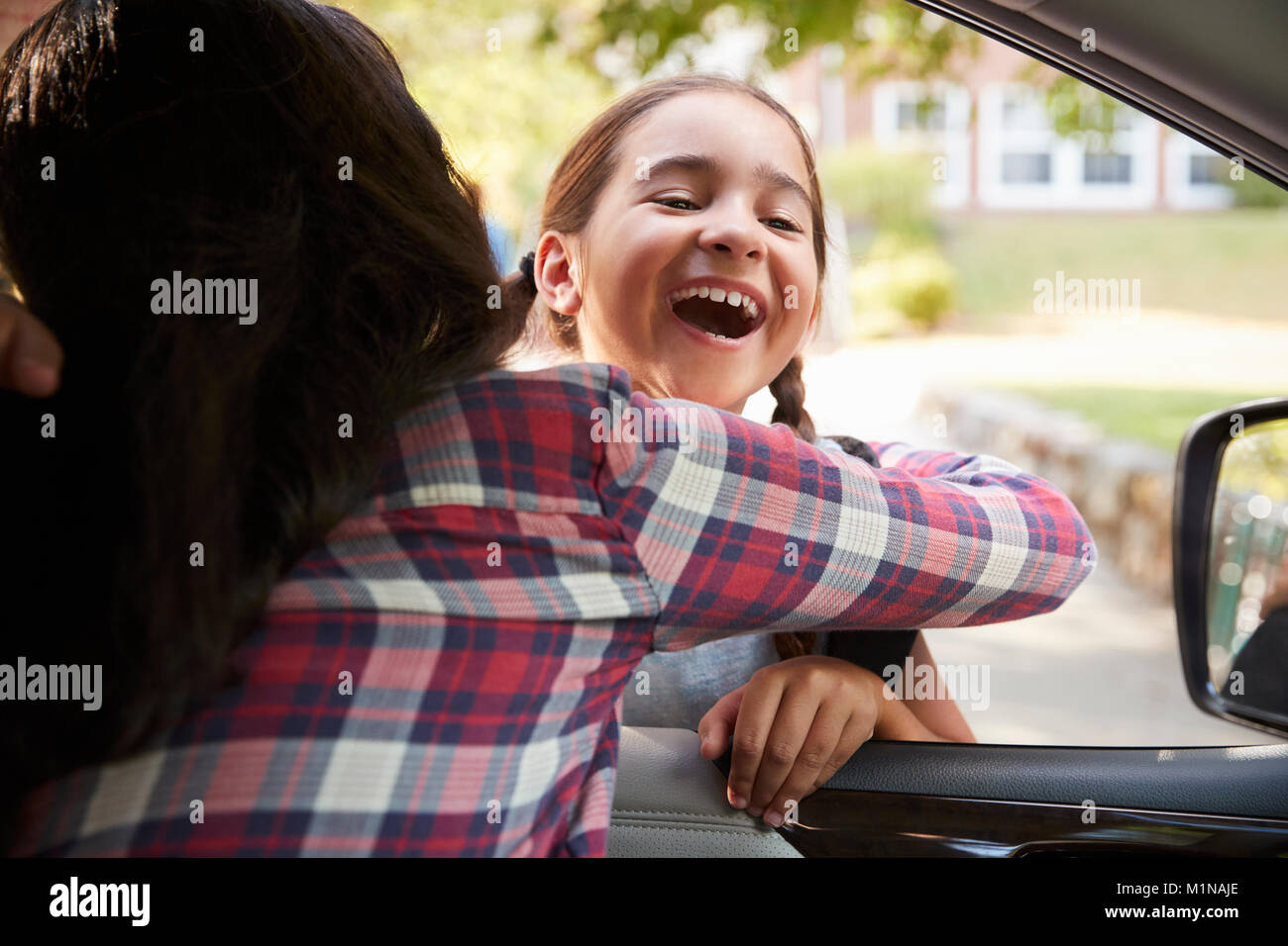 Mother In Car Collecting Daughter In Front Of School Gates Stock Photo